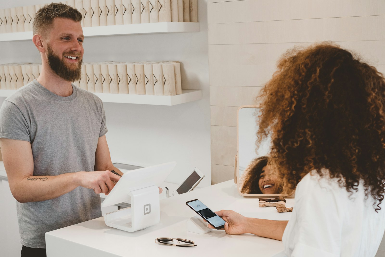 A customer paying by phone at a small shop counter