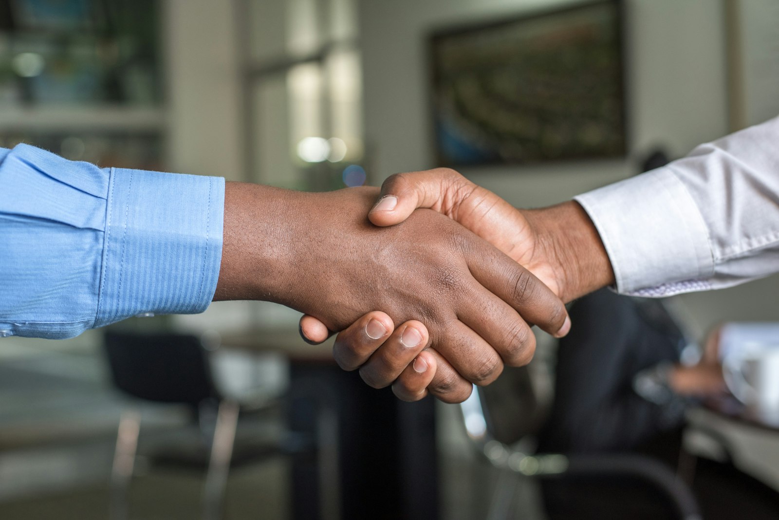 Two people shaking hands over a desk